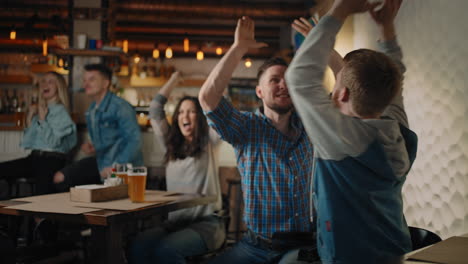 Friends-are-watching-together-emotionally-watching-football-on-TV-in-a-bar-and-celebrating-the-victory-of-their-team-after-scoring-a-goal.-Watch-hockey.-The-scored-puck.-Fans-in-the-pub
